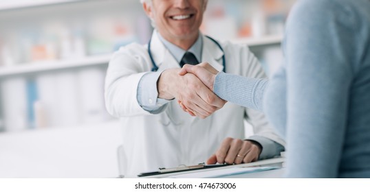 Doctor And Patient In The Office Shaking Hands, Healthcare And Assistance Concept