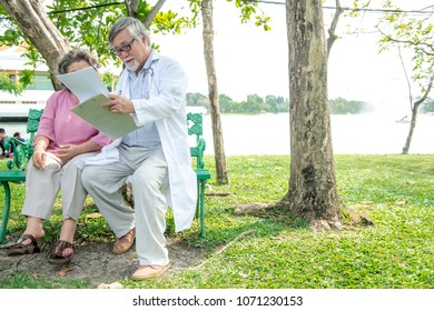 Doctor with patient in park. Senior chinese male doctor sitting together with chinese female patient. Talking and examine her.