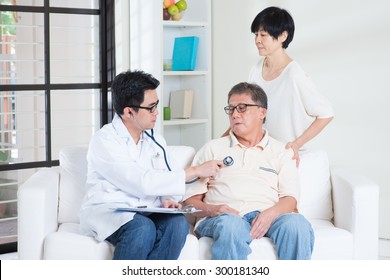 Doctor And Patient. Sick Asian Old Man Consult Family Doctor, Sitting On Sofa. Senior Retiree Indoors Living Lifestyle.