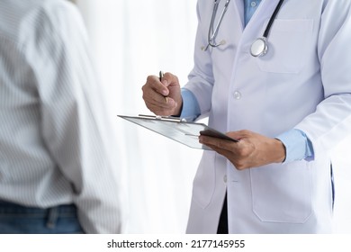 Doctor and patient sitting and talking at medical examination at hospital office, close-up. Therapist filling up medication history records. Medicine and healthcare concept. - Powered by Shutterstock