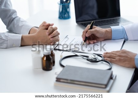 Doctor and patient sitting and talking at medical examination at hospital office, close-up. Therapist filling up medication history records. Medicine and healthcare concept. Stock fotó © 