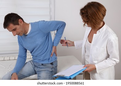 Doctor And Patient Suffering From Low Back Pain During Medical Exam. Chiropractic, , Physiotherapy Concept.