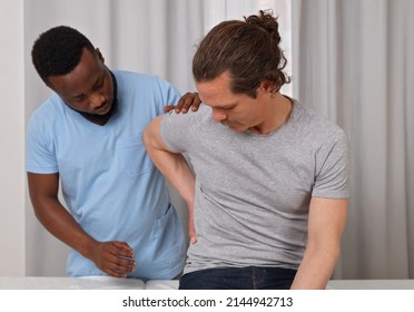 Doctor And Patient Suffering From Low Back Pain During Medical Exam. Chiropractic, , Physiotherapy Concept.