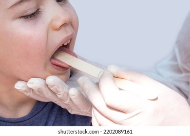 Doctor Pediatrician Checking Boy Kid Throat With Wooden Spatula.spatula On Tongue,wide Open Mouth Crying Upset Sad Child.medical Assistance Hands In White Surgical Gloves.sore Throat Redness Angina