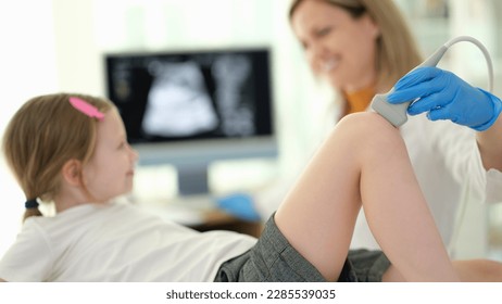 Doctor pediatrician conducting ultrasound examination of knee joint of child in clinic closeup - Powered by Shutterstock