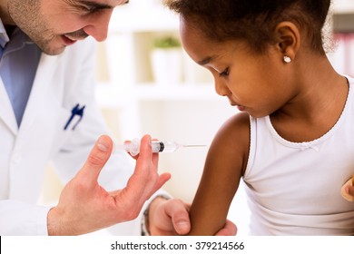 Doctor pediatrician injecting vaccine to cute african girl - Powered by Shutterstock - Get 15% off with code: PIKWIZARD15