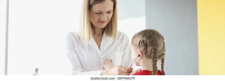 Doctor Pediatrician Putting Stethoscope On Little Girl In Clinic. Childcare Concept