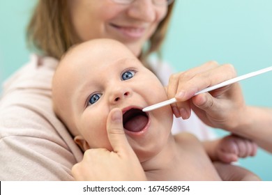 Doctor pediatrist examining childs throat and tooth. Mom holding baby with hands while health checkup. Medicine, healthcare ,pediatry and people. Children healthcare and disease prevention concept - Powered by Shutterstock