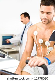 Doctor Performing An EKG Test On Young Male Patient. Real People, Real Location, Not A Staged Photo With Models.