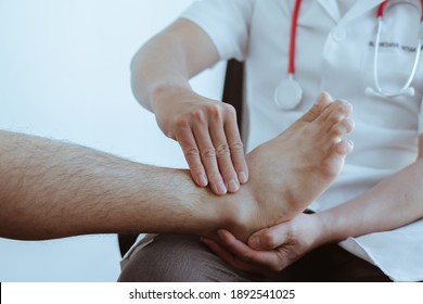 A Doctor Or Physical Therapist Examines Ankle Pain And Gives Advice In A Rehabilitation Center.