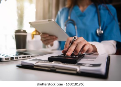 Doctor physician with stethoscope calculate medical fee costs & revenue. practitioner use calculator at Clinic.