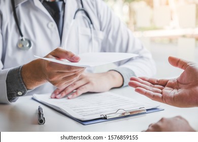 Doctor or physician writing diagnosis and giving a medical prescription to male Patient - Shutterstock ID 1576859155
