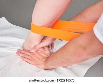 Doctor Or Physio Therapist Treating A Patient's Leg With A Therapy Belt, No Faces Shown