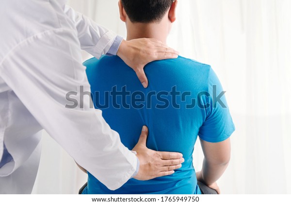 Doctor physiotherapist doing healing treatment\
on man\'s back.Back pain patient, treatment, medical doctor, massage\
therapist.office\
syndrome