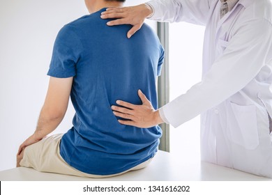 Doctor physiotherapist treating lower back pain patient after while giving exercising treatment on stretching in the clinic, Rehabilitation physiotherapy concept. - Shutterstock ID 1341616202