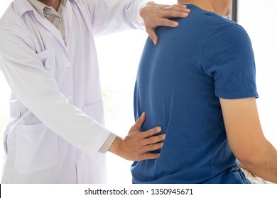 Doctor Physiotherapist Treating Lower Back Pain Patient After While Giving Exercising Treatment On Stretching In The Clinic, Rehabilitation Physiotherapy Concept.