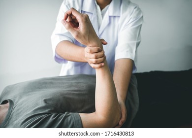 Doctor Or Physiotherapist Working Examining Treating Injured Arm Of Athlete Male Patient, Stretching And Exercise, Doing The Rehabilitation Therapy Pain In Clinic.