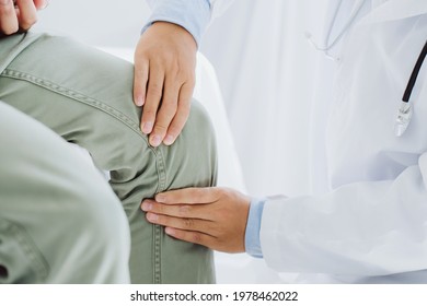 Doctor Physiotherapist Working Examining Treating Injured Knee Of Patient, His Using The Handle To The Patient Knee To Check For Pain.