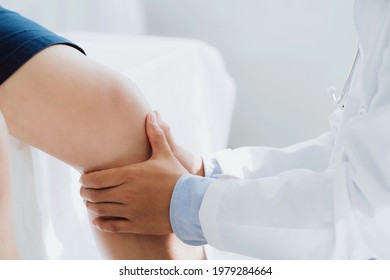 Doctor Physiotherapist Working Examining Treating Injured Knee Of Patient, His Using The Handle To The Patient Knee To Check For Pain.