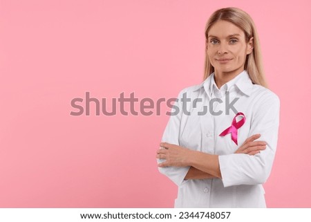 Doctor with pink ribbon on color background, space for text. Breast cancer awareness