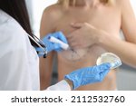 Doctor plastic surgeon holding breast implant and drawing with marker on patient skin closeup
