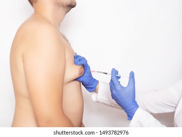 Doctor plastic surgeon injects a man in the chest to correct and reduce fat and breast size, copy space, liposuction