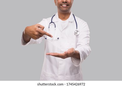 Doctor Pointing at Empty Open Hand in front of Chest Close Up Isolated. Indian Man Doctor Advertisment Concept - Powered by Shutterstock