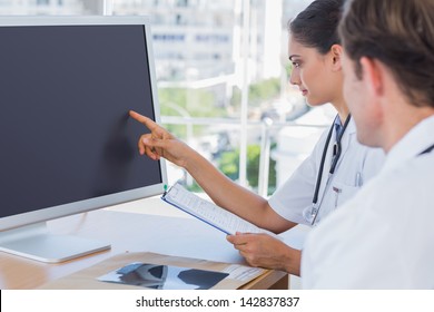 Doctor Pointing At The Screen Of A Computer While Working With A Colleague