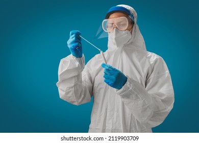A doctor in PPE and face shield holding test tube COVID-19 swab collection kit. Test tube for taking OP NP patient specimen sample, PCR DNA testing protocol process. PCR test concept. - Shutterstock ID 2119903709