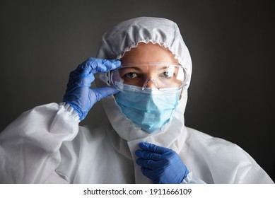 Doctor In PPE Kit Suit, Female Physician Wearing Goggles And Face Mask, Portrait Of Nurse In Professional Coverall Due To COVID-19 Or Smallpox. Portrait Of Medical Worker. Care And Safety Concept. 