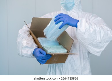 Doctor in PPE and medical mask opens a box and show the packing of a new surgical masks, which he must take during an pandemic of covid-19. This face masks will help to prevent coronavirus