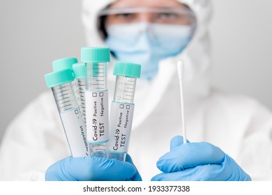 Doctor in PPE suit and face mask demonstrates test tubes with coronavirus Covid-19 samples. - Powered by Shutterstock