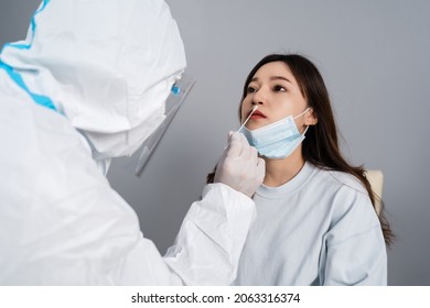 doctor with PPE suit test coronavirus(covid-19) to young woman by nasal swab  - Shutterstock ID 2063316374