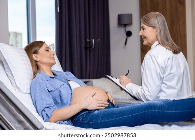 Doctor and pregnant woman talking in the clinic and doctor writing the anamnesis - Powered by Shutterstock