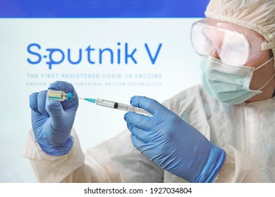 A Doctor Prepares A Vaccine Against The Coronavirus Covid 19 On The Background Of The Sputnik V Logo. January 18, 2021, Barnaul, Russia.