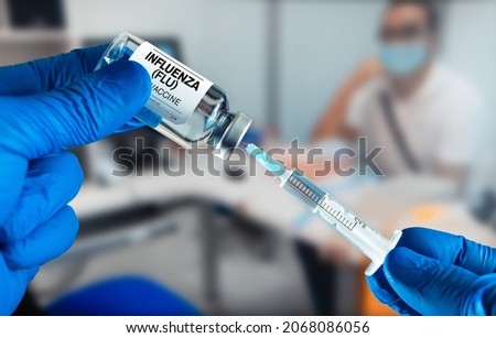 Doctor preparing a dose of Influenza (Flu) vaccine for a patient. Doctor with Influenza (Flu) or Grippe vaccine bottle for the annual flu disease prevention campaign