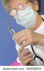 doctor preparing injection of COVID-19 vaccine for prevention of coronavirus with glass syringe and large needle
