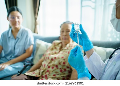 Doctor Preparing A Vaccine In Syringe For Injecting On Asian Elder Woman Arm Close Up With Copyspace. Granddaughter Take Her Grandmother To See A Doctor In Hospital And Getting A Vaccination.