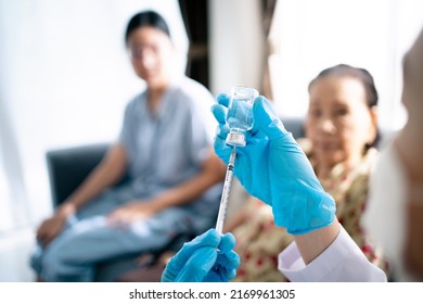 Doctor Preparing A Vaccine In Syringe For Injecting On Asian Elder Woman Arm Close Up With Copyspace. Granddaughter Take Her Grandmother To See A Doctor In Hospital And Getting A Vaccination.