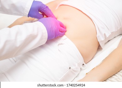 The doctor probes the lower abdomen in a girl who has pain and inflammation of the bladder. The concept of diseases in girls cystitis, kidney stones, dysmenorrhea