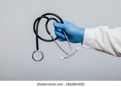 Doctor in a protective glove holding a stethoscope isolated on a gray background