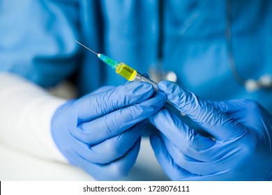 Doctor In Protective Gloves Holding Syringe Filled With Yellow Liquid,closeup Detail,platelet Rich Convalescent Patient Blood Plasma Used As Treatment For COVID-19 Patient,antibody Transfusion Concept