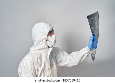 A Doctor In A Protective Suit And Mask Looks At The Results Of A CT Scan Of The Lungs