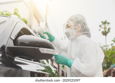 Doctor in protective suit PPE holding test kit. Medical worker performing drive-thru Covid-19 test, taking nasal swab sample patient through car window, PCR diagnostic, Rapid antigen test kit (ATK)