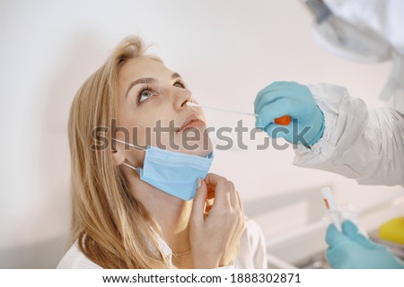 Doctor protective suit and surgical face mask. Cotton swab from the throat and nose of the patient's. Coronavirus test, test for covid-19 infection in a pandemic. [[stock_photo]] © 