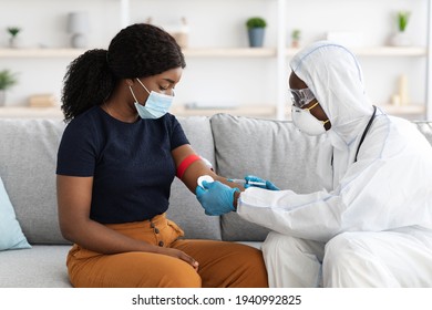 Doctor In Protective Suit Taking Blood Sample For Female Patient