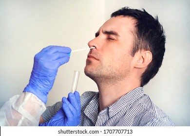 A doctor in a protective suit taking a nasal swab from a person to test for possible coronavirus infection. Nasal mucus testing for viral infections. - Shutterstock ID 1707707713