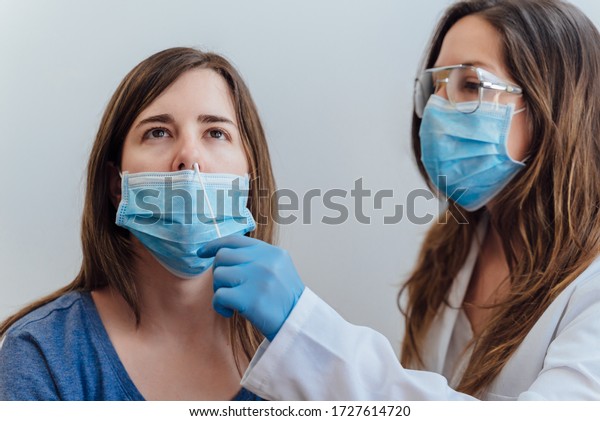 A doctor in a protective suit taking a\
nasal swab from a person to test for possible coronavirus\
infection. Nasal mucus testing for viral\
infections.