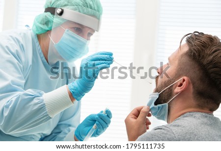 Doctor in a protective suit taking a throat and nasal swab from a patient to test for possible coronavirus infection