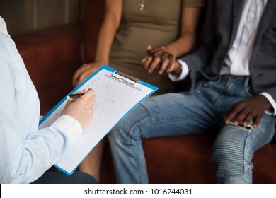 Doctor or psychologist filling medical patient information form holding clipboard consulting african american couple, marriage counseling, family therapy, fertility treatment for infertility concept